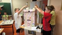Die Schüler und Schülerinnen der Klasse 4 arbeiten an einem eigenen Hundertwasserhaus. Sie kleben, basteln und malen  mit verschiedenen Materialien. Das Ergebnis präsentieren sie im Schulgebäude.